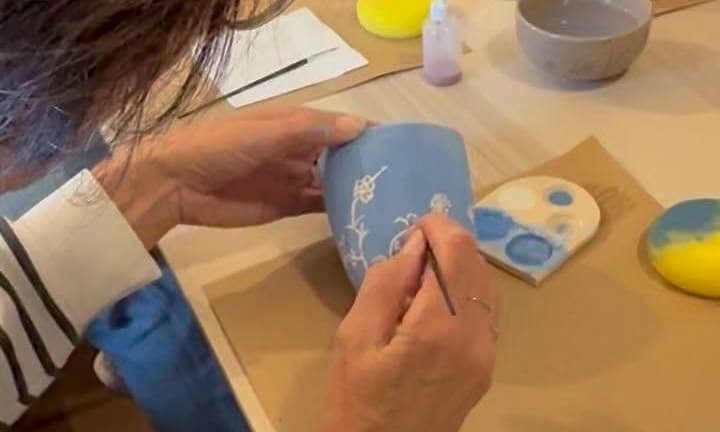 Een deelnemer beschildert keramiek in het atelier